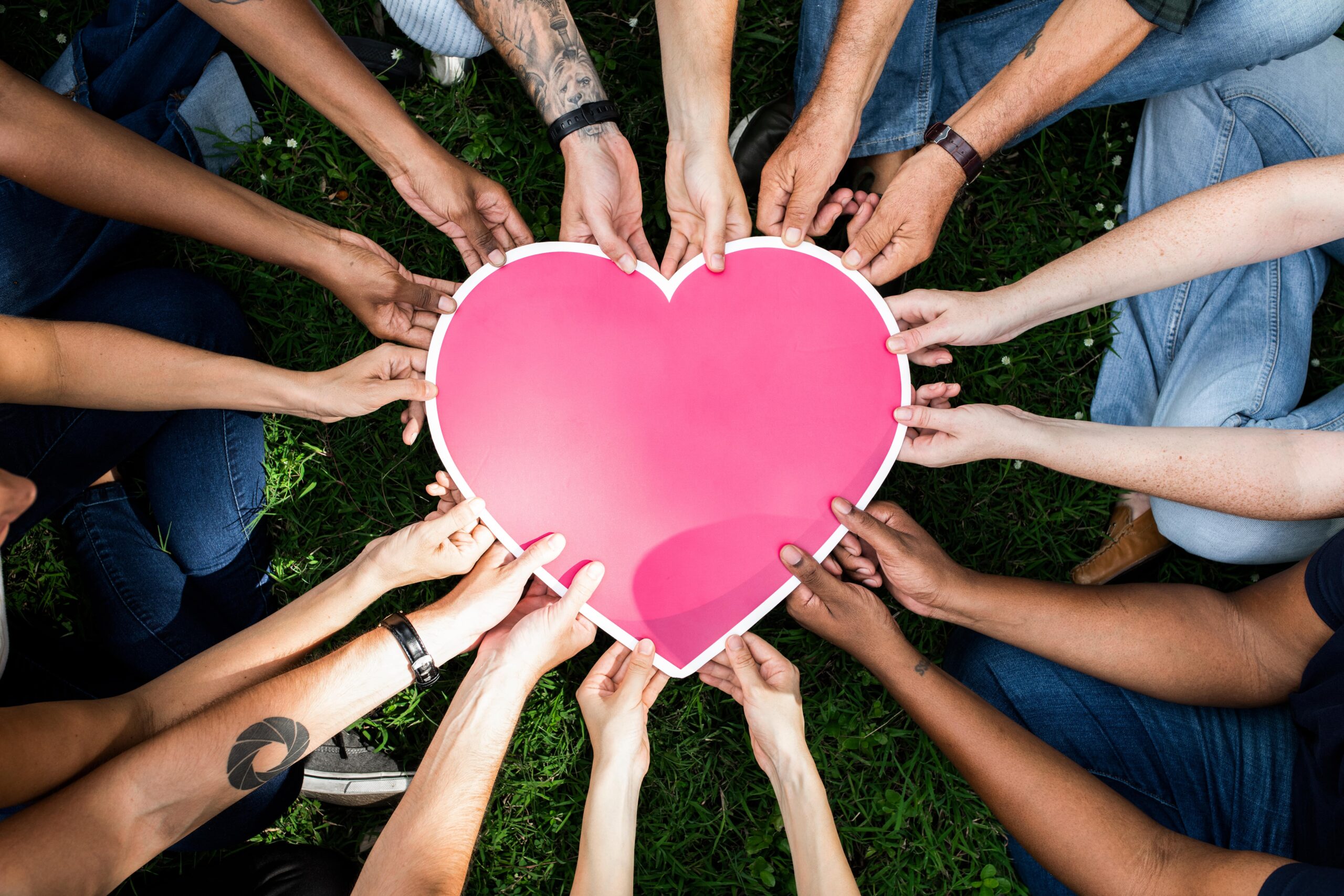 Group of People Coming Together to Hold A Red and White Paper Heart