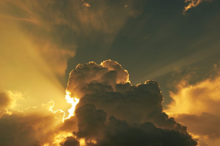 Sun and beams breaking through and going around large fluffy clouds